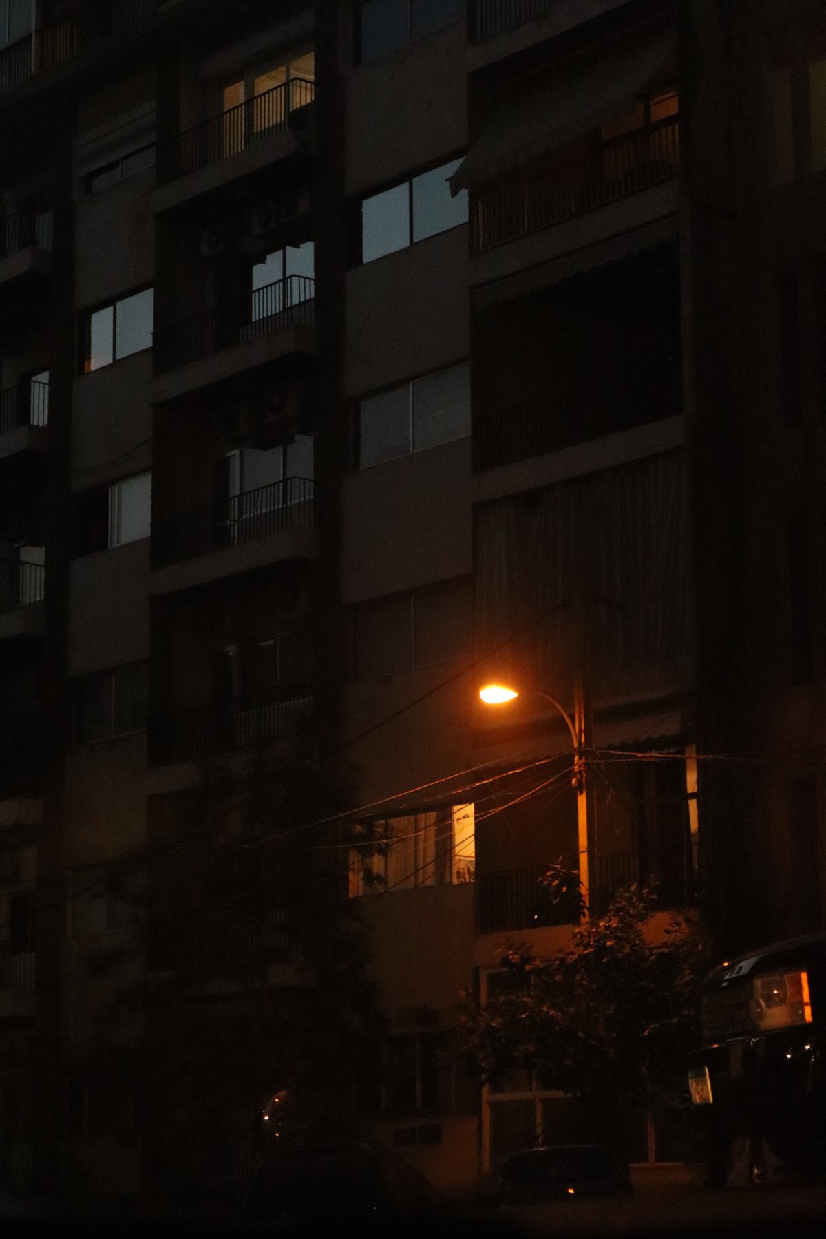 A single streetlight glowing against a dark apartment building