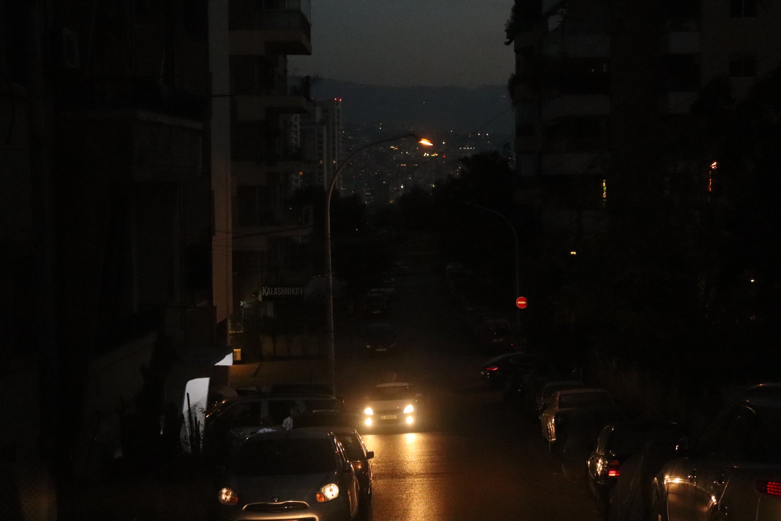 Dark street with car headlights and the city below