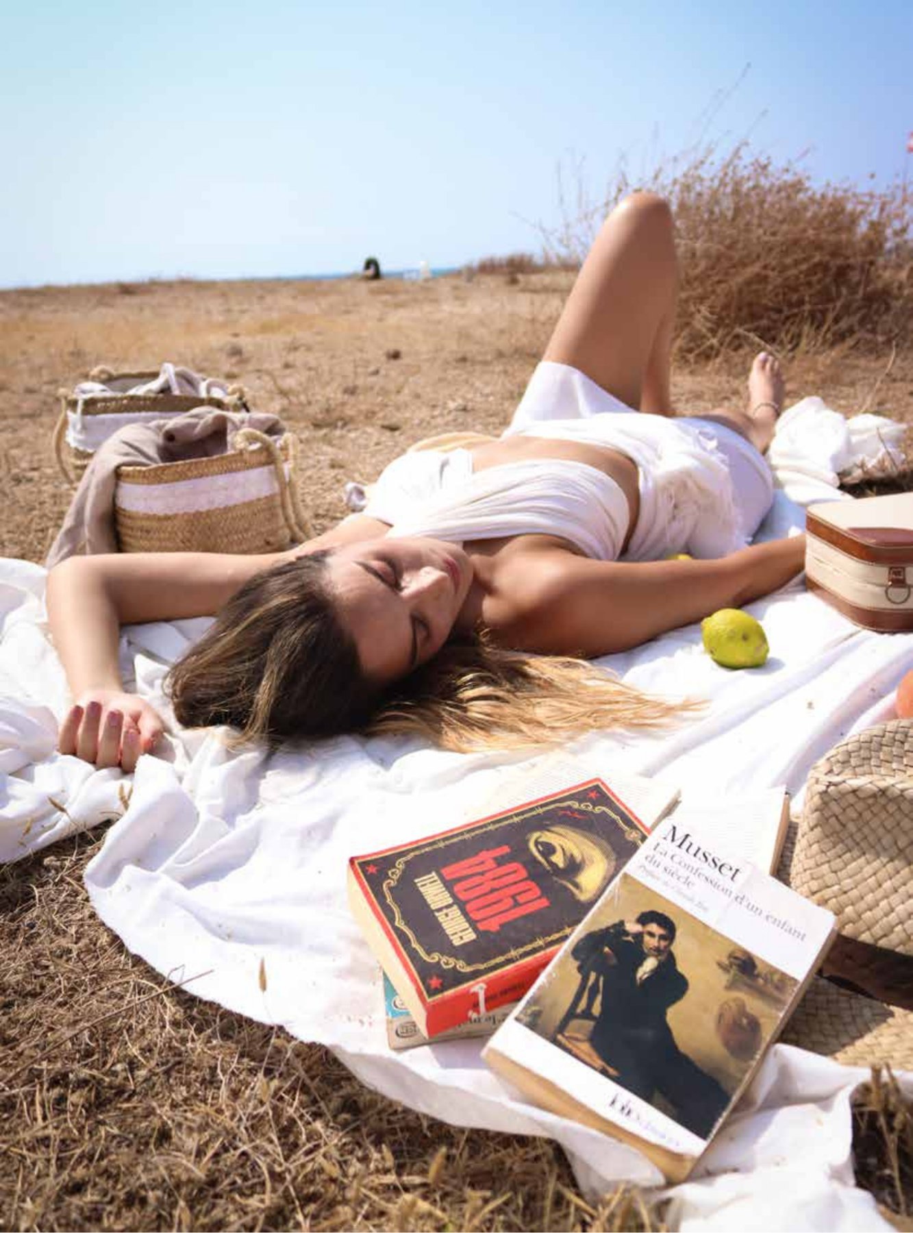 Woman resting on a picnic blanket with books by Orwell and Musset