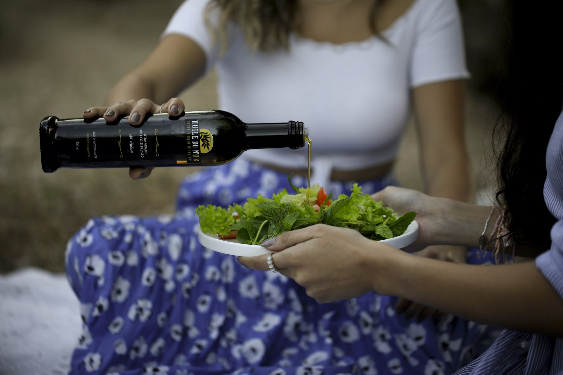 Olive oil poured over a fresh salad at a picnic
