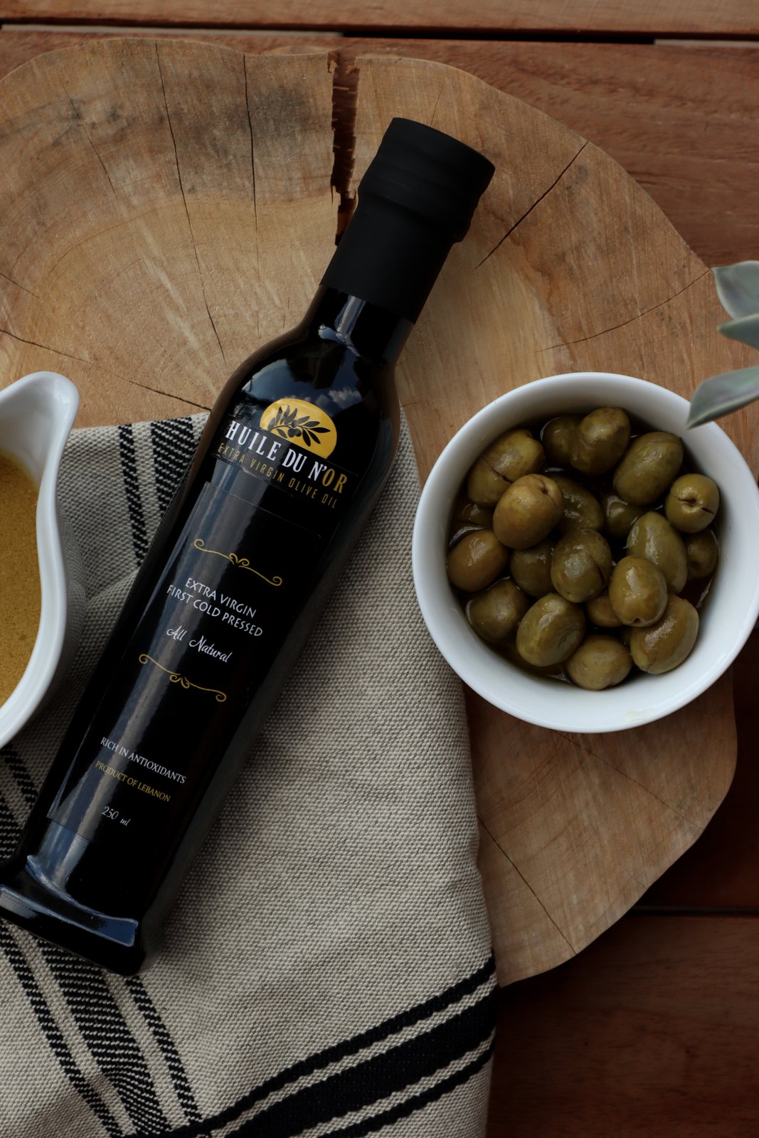 Bottle on a wooden board with a bowl of green olives