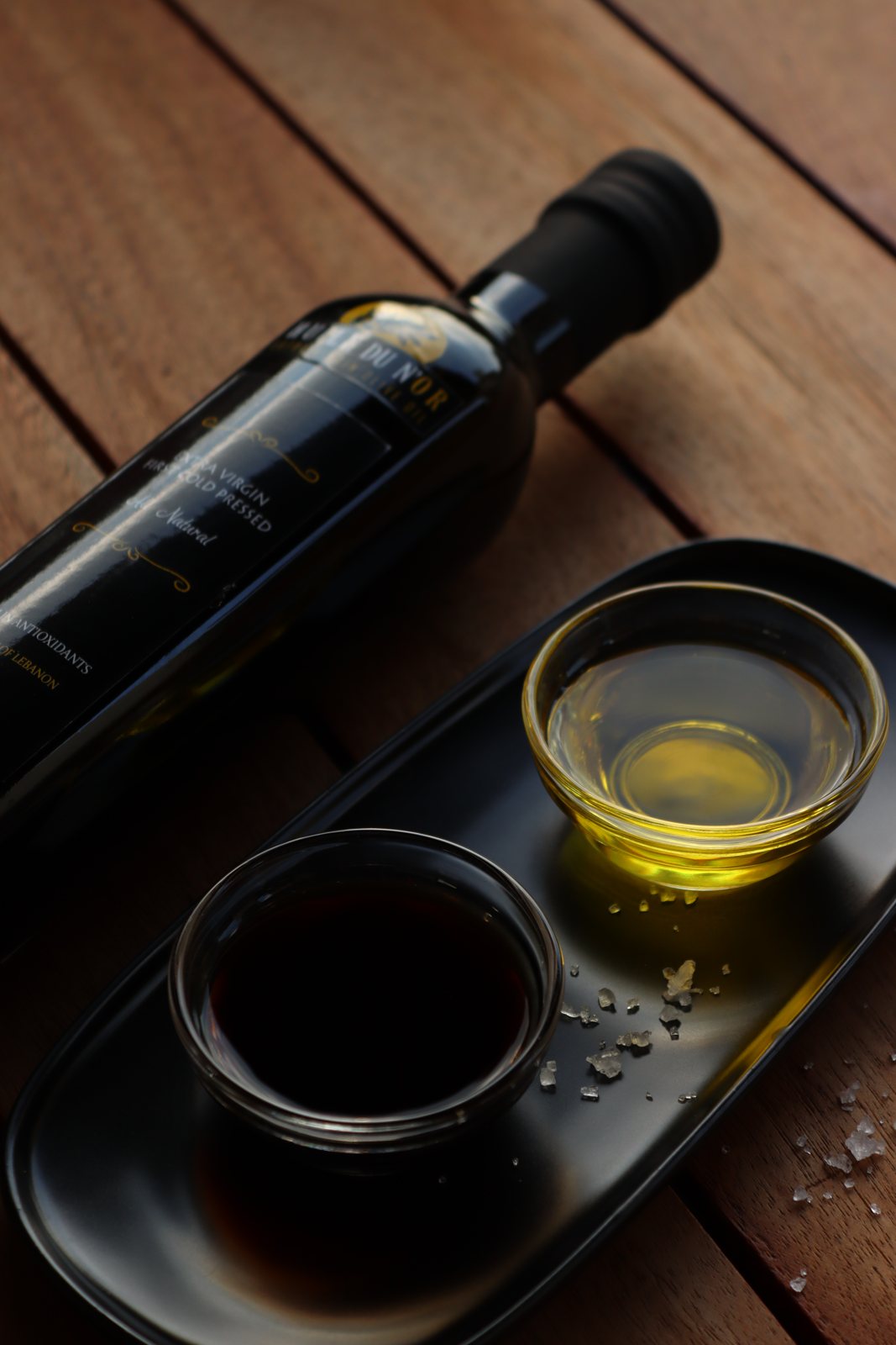 Bottle beside small bowls of olive oil and balsamic with sea salt